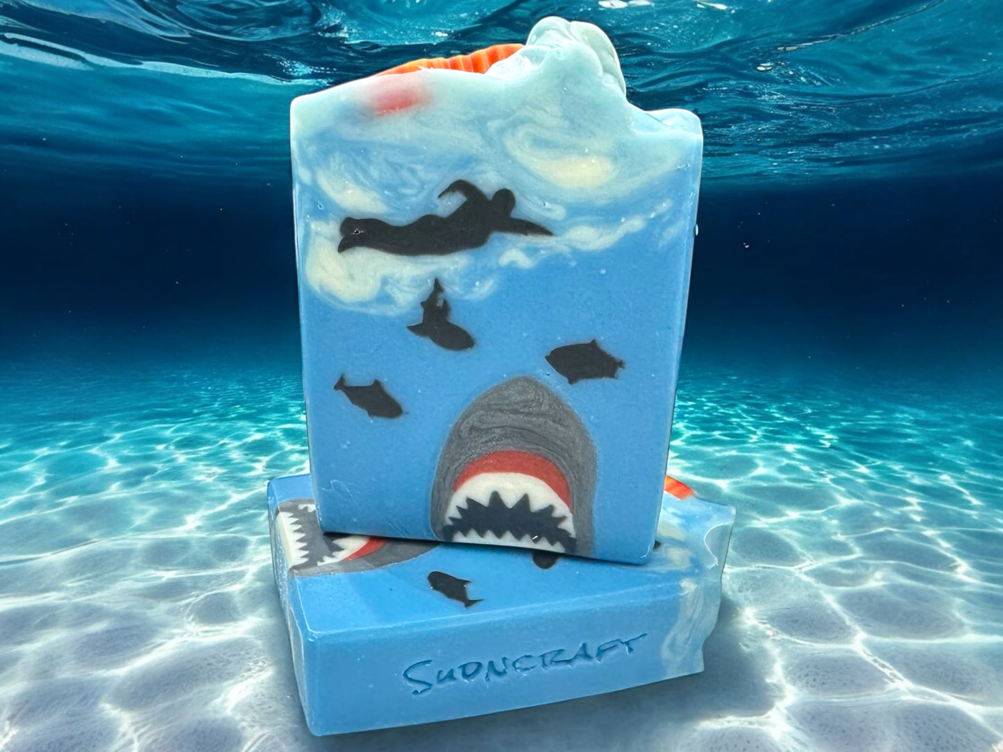 Each bar features:
A playful shark design
 A surfboard topper with a bite taken out of it
A refreshing tropical scent perfect for summer